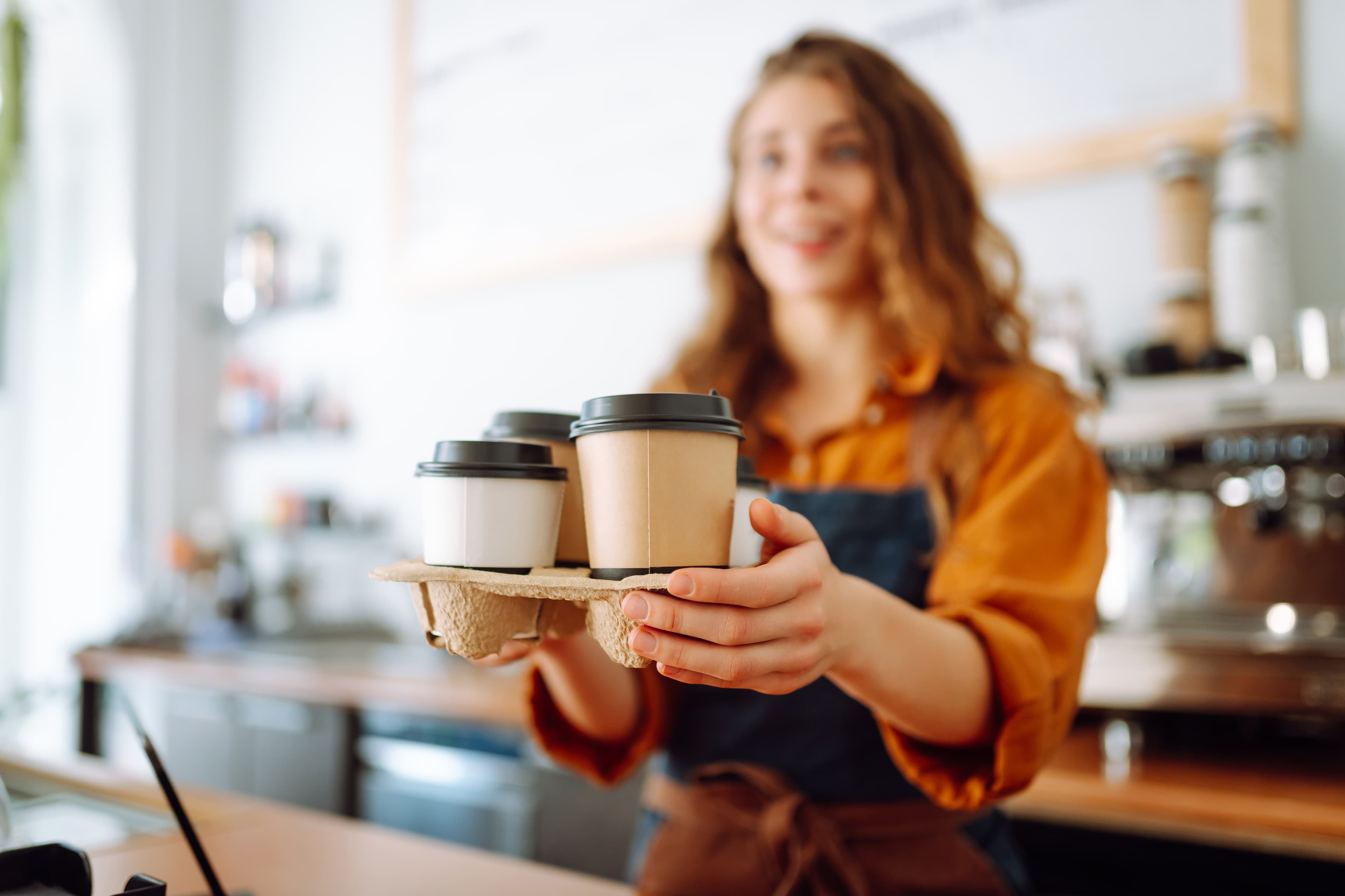 Cafe worker handing coffee cups on a pickup tray